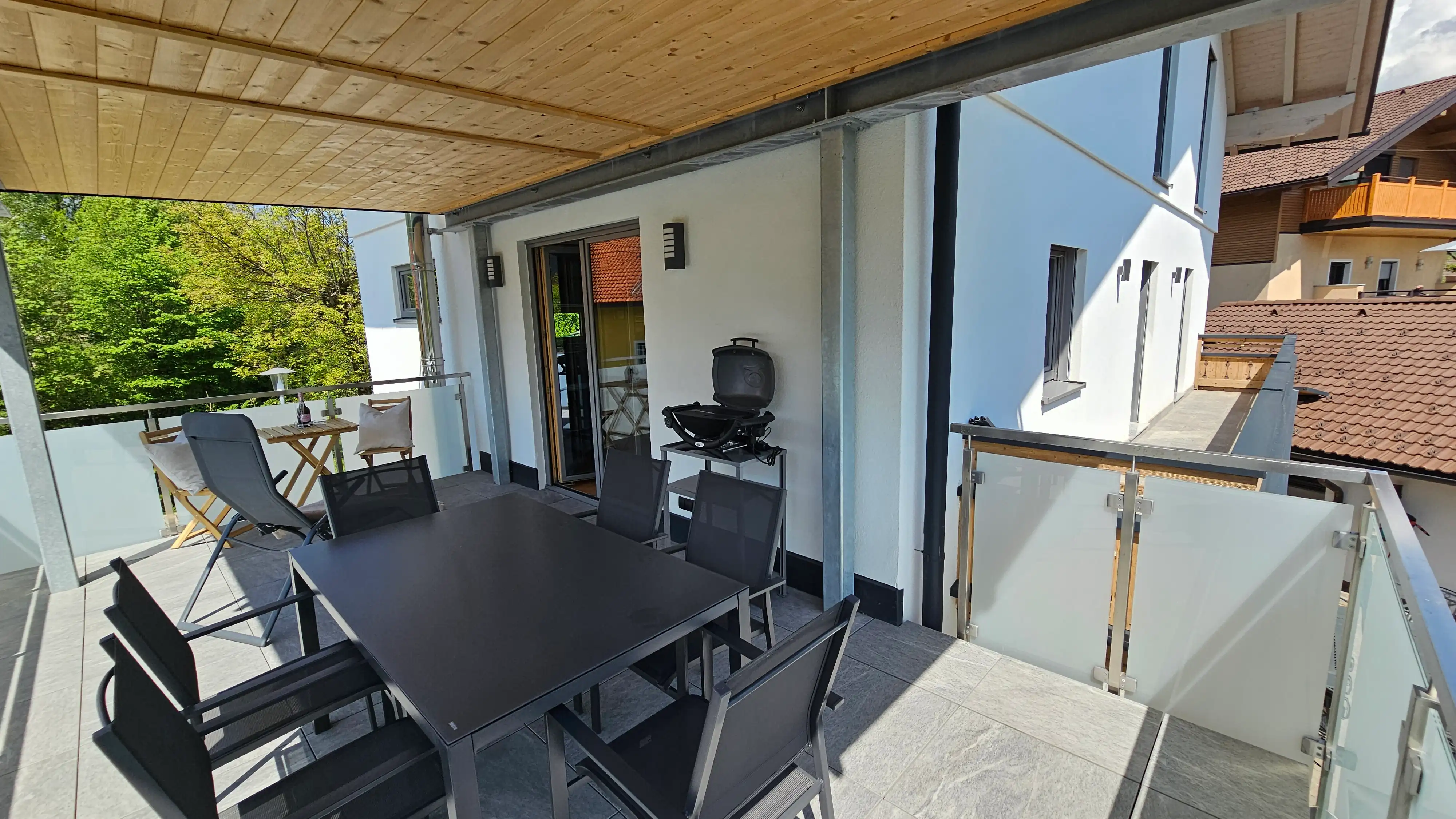 Überdachter Balkon mit Esstisch, Stühlen und Grill